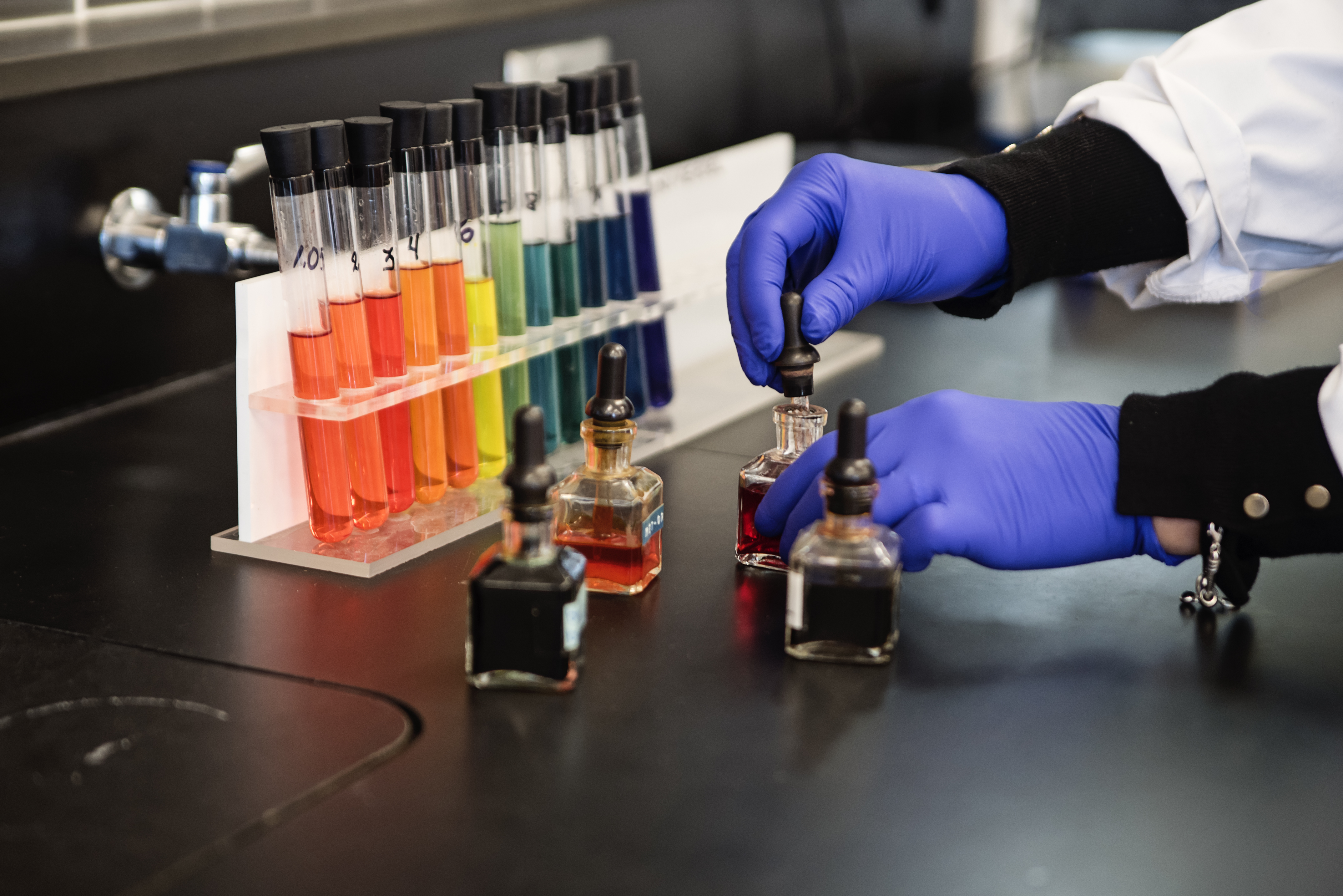 Een laborant experimenteert met proefbuizen in regenboogkleuren