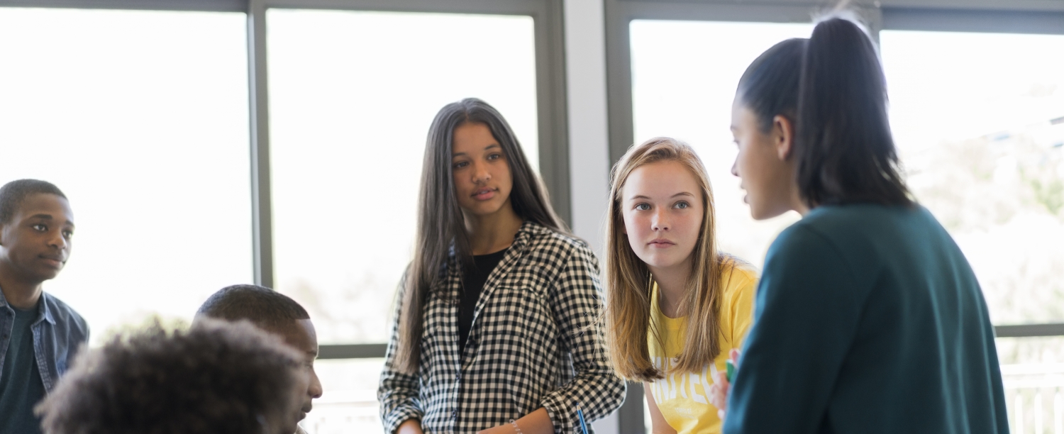 groepje leerlingen zitten bovenop schoolbank
